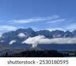 Mountain Range with Clouds and Trees Under a Blue Sky
