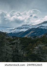 A mountain range covered in snow with a cloudy sky in the background