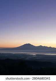 Mountain range illuminated by soft dawn light above a mist-covered valley. Photographed from a high vantage point during early morning, the expansive natural scenery showcases layered landscapes, clear skies, and a peaceful atmosphere ideal for travel and nature themes.