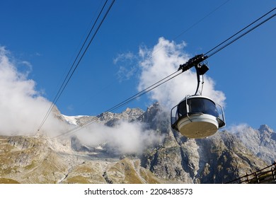 Mountain Range of the Italian Alps on a Sunny Summer Day, close-up view of the Rocks, Blue Sky with Clouds and The Cableway.