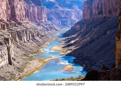 A mountain range on a sunny day, featuring rocky cliffs, lush greenery and a winding river flowing through the center of the image - Powered by Shutterstock