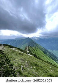 The mountain range with the path in the middle and thick gray rainy cloud hanging over it 