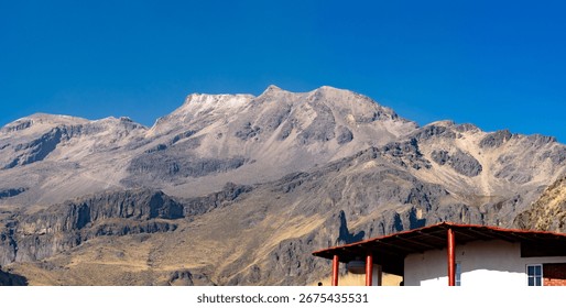 A mountain range with a red building in the foreground. The mountain range is covered in snow and the building is made of wood. Iztacihuatl volcano mexico,