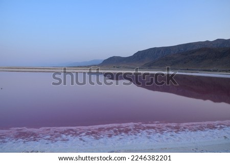 mountain range reflects in the evening light in the pink coloured water of pink lake Shiraz, Iran