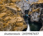 A mountain range with a river running through it. The water is clear and the rocks are grey