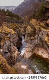 A mountain range with a river running through it. The water is clear and the rocks are grey