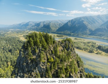 A mountain range with a river running through it. The mountains are covered in trees and the river is clear. The sky is blue and there are no clouds