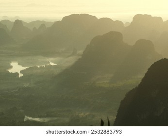 A mountain range with a river running through it. The mountains are covered in trees and the sky is hazy - Powered by Shutterstock