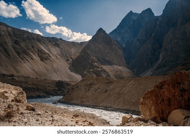 A mountain range with a river running through it. The mountains are covered in snow and the river is clear