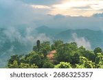 A mountain range with trees and clouds in the sky. The clouds are white and fluffy. The trees are green and spread out across the mountain. Tamil nadu