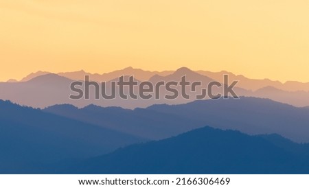 Mountain range of tropical rainforest and sky turned blue and orange colors of winter season at sunset.