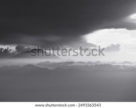 A mountain range is visible in the distance with a dark cloud in the sky. The sky is overcast and the clouds are low, giving the image a moody and somber feel