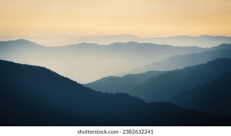 Mountain range with visible silhouettes through the morning colorful fog.Calm evening landscape in the mountains at sunset. Photo wallpaper. Natural background. Panorama. Carpathian Mountains, Ukraine - Powered by Shutterstock