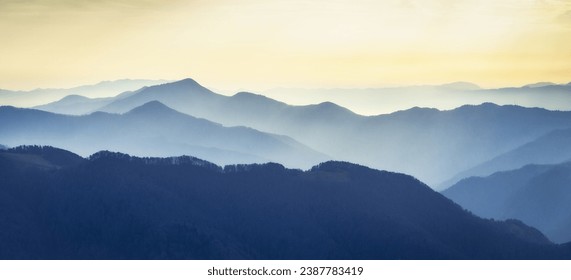 Mountain range with visible silhouettes through the  colorful fog. Photo wallpaper. Natural background. Panorama. Carpathian Mountains, Ukraine - Powered by Shutterstock