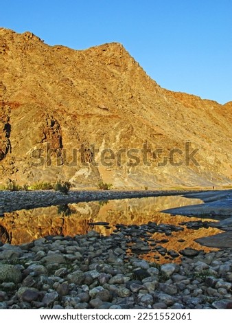 Mountain reflecting into a calm pool on a clear early morning along the Fish River Canyon, Namibia