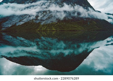 Mountain reflection on a Norwegian fjord on a cloudy day