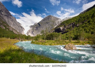 The mountain river, against the woody mountains, originating from a thawing glacier, Norway