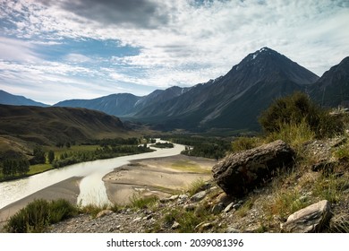 Mountain River Flows Through The Breathtaking Plain Under A Large Cloud Somewhere In This Amazing Panoramic Mountains And Mountain Peaks With No People