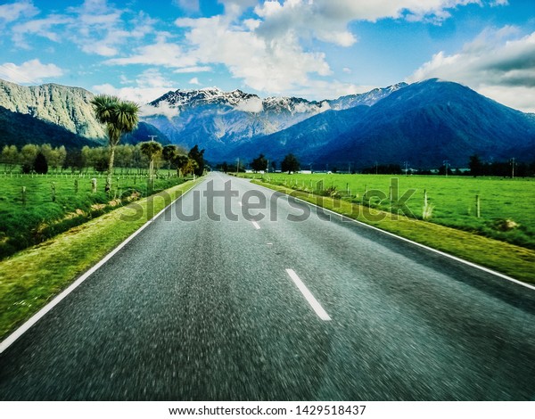 Mountain road with colorful landscape of high\
snowy summits to live adventures by car, unfocused edges to give\
impression of speed when\
driving.