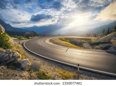 Mountain road at colorful sunset in summer. Dolomites, Italy. Beautiful curved roadway, rocks, stones, blue sky with clouds. Landscape with empty highway through the mountain pass in spring. Travel - Powered by Shutterstock