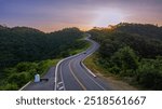 A mountain road with many curves winding through lush and lush forests and beautiful natural views on both sides during the morning sunrise in Nan Province, Thailand, Asia.