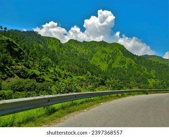 Mountain road: Side view, clouds, blue sky.