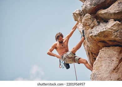 Mountain Or Rock Climbing, Cliff Hanging And Adrenaline Junkie Out On Adventure And Checking His Safety Equipment, Hook And Rope. Fearless Man Doing Fitness, Exercise And Workout During Extreme Sport