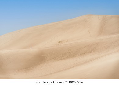 A mountain sand dunes with footmarks against a blue sky