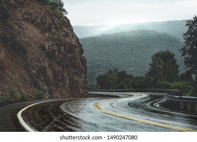 Mountain scenic winding road after rain. Green forest hills in the background covered by fog. Cape Breton, Cabot Trail, Nova Scotia, Canada - Powered by Shutterstock