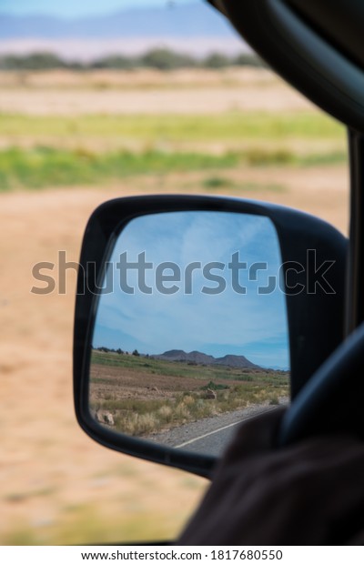 Mountain\
seen far away through the side mirror of a\
car