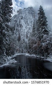 Mountain side with snow, trees, and clouds