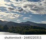 Mountain Silhouette and Dramatic Clouds Over Green Forest.Scenic view of mountains with dramatic clouds and lush green forest.Perfect natural landscape background.