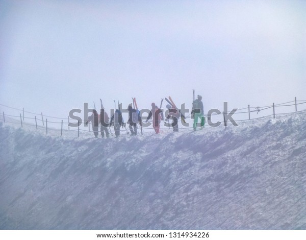 Mountain skiers go\
together on danger mountain ridge in  snow storm and danger of\
avalanche, mountain peak Aiguille du Midi in France above ski\
village Chamonix\
Mont-Blanc