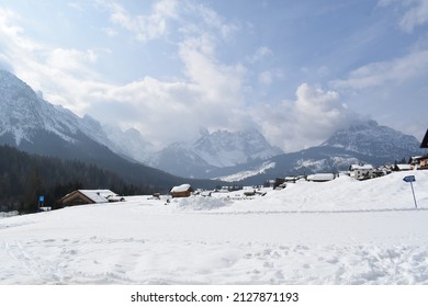 Mountain snowy landscape in a winter day. Snow and blue sky with clouds. Typical mountain village landscape. Dolomiti. Italian Alps. Italy