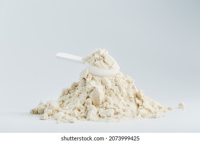 A mountain of soy protein isolate in powder with a measuring spoon on a white background. Vegetarian sports nutrition for cocktails - Shutterstock ID 2073999425
