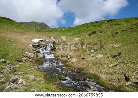 A mountain stream running down through grassy plains of Rila mountains, crossing the famous 