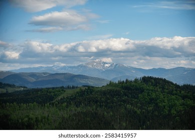 Mountain summit view under a cloudy sky in a lush landscape with green forests and distant peaks