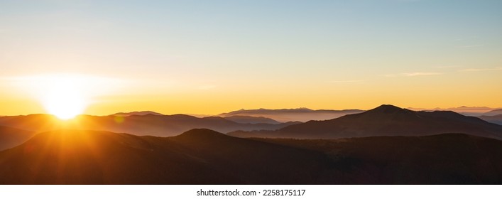Mountain sunrise header. Mountain silhouettes and rays of the rising sun - Shutterstock ID 2258175117