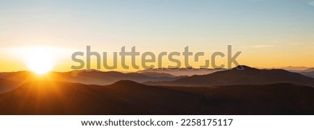 Mountain sunrise header. Mountain silhouettes and rays of the rising sun