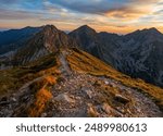 Mountain trail leading along the mountain ridge of beautiful mountains with autumn grass and colorful sky. Western Tatras, High Tatras, Slovakia, Poland. Discovering hiking in a colorful autumn.