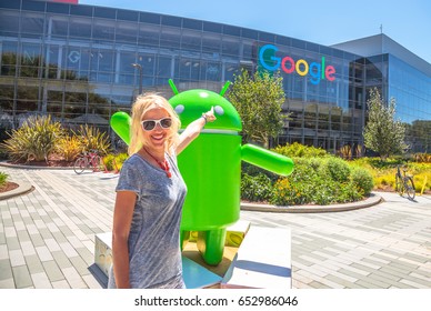 Mountain View, California, USA - August 15, 2016: Smiling Woman Showing Google Sign On Facade Of Google Headquarters Building. Young Tourist Visiting Popular Technology Company In Silicon Valley.