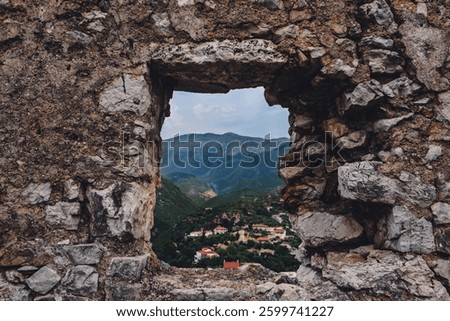 Mountain village houses view through Himara castle fortification wall. Mountainous settlement looking down from Old Himara fort, ruined historic landmark and tourist attraction in Albania.