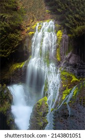 A mountain waterfall flows over the rocks. Waterfall cascade on mossy rocks. Mountain waterfall view. Waterfall cascade
