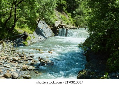 Mountain Waterfall In The Forest, A Large Noisy Stream Of Water, A Wild Natural Spring In A Remote Place.