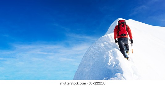 Mountaineer arrive to the summit of a snowy peak. Concepts: determination, courage, effort, self-realization. Clear sky, sunny day, winter season. Large copy-space on the left. European Alps, Europe.