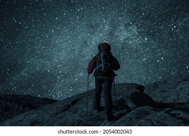 Mountaineer With Backpack On Rock Enjoying View Of Night Sky With Stars, Hiking Lifestyle, Man On Top. Retro Stylization, Vintage Film Filter