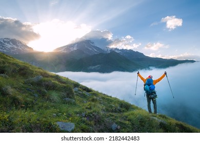 Mountaineer Descending Kazbek 5054m Mountain With Backpack, Helmets High Mountaineering Boots Standing Rising Arms Up With Trekking Poles, Enjoying Sunset After Successful Ascending, Caucasus, Georgia