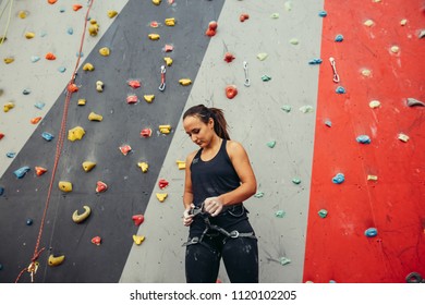 Mountaineer fitting harness on her waist preparing for climbing on high colorful artificial rock. - Powered by Shutterstock