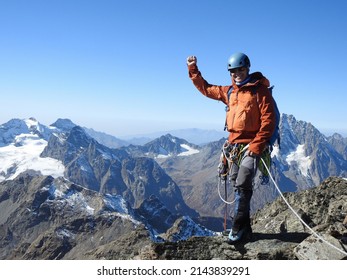 mountaineer with ice ax stands on the top of a mountain in the background of the landscape of snowy mountains