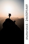 Mountaineer on the summit of a rock pinnacle backlit at sunrise in the Pyrenees